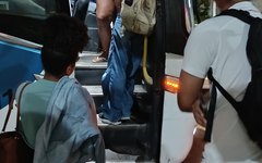 Alunos sem esperando para entrar no ônibus lotado.