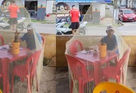 Cliente usa mosquiteiro para beber cerveja em bar em Alagoas