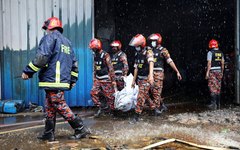Equipes de resgate carregam corpos de vítimas do incêndio em fábrica